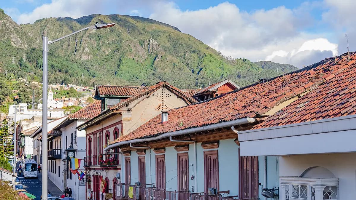 Casas coloniales de techos de teja en La Candelaria de Bogotá con cerros verdes al fondo