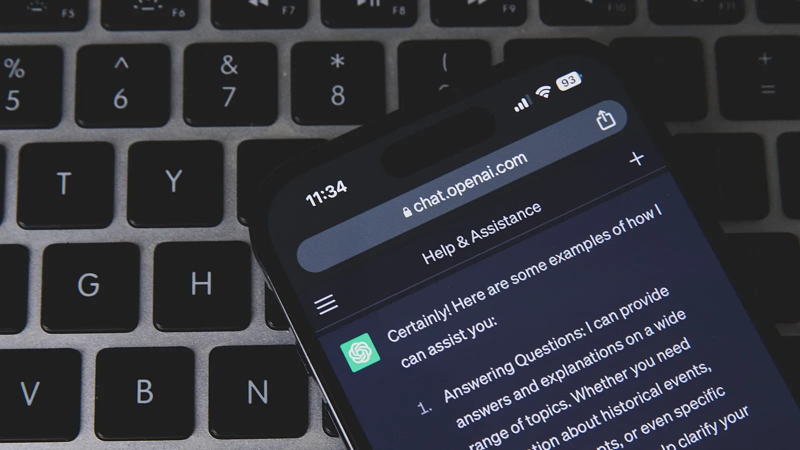 Smartphone con ChatGPT abierto apoyado sobre un teclado de computador