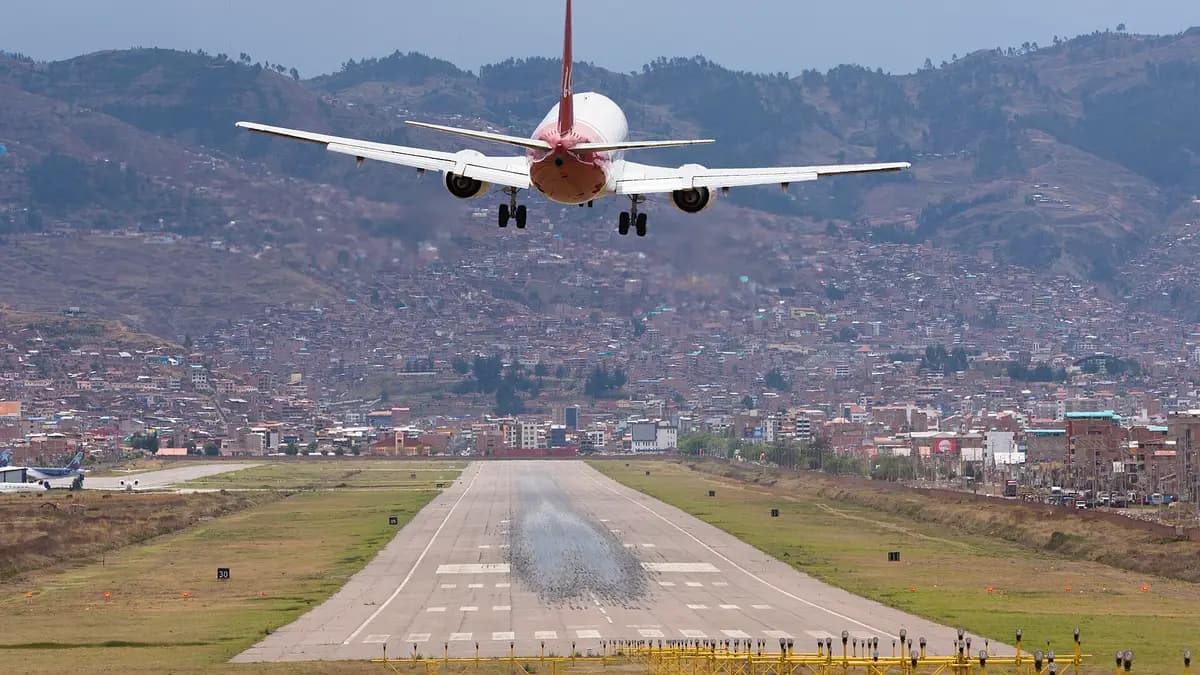 Avión aterrizando en el aeropuerto de Cusco con la ciudad y los cerros de fondo