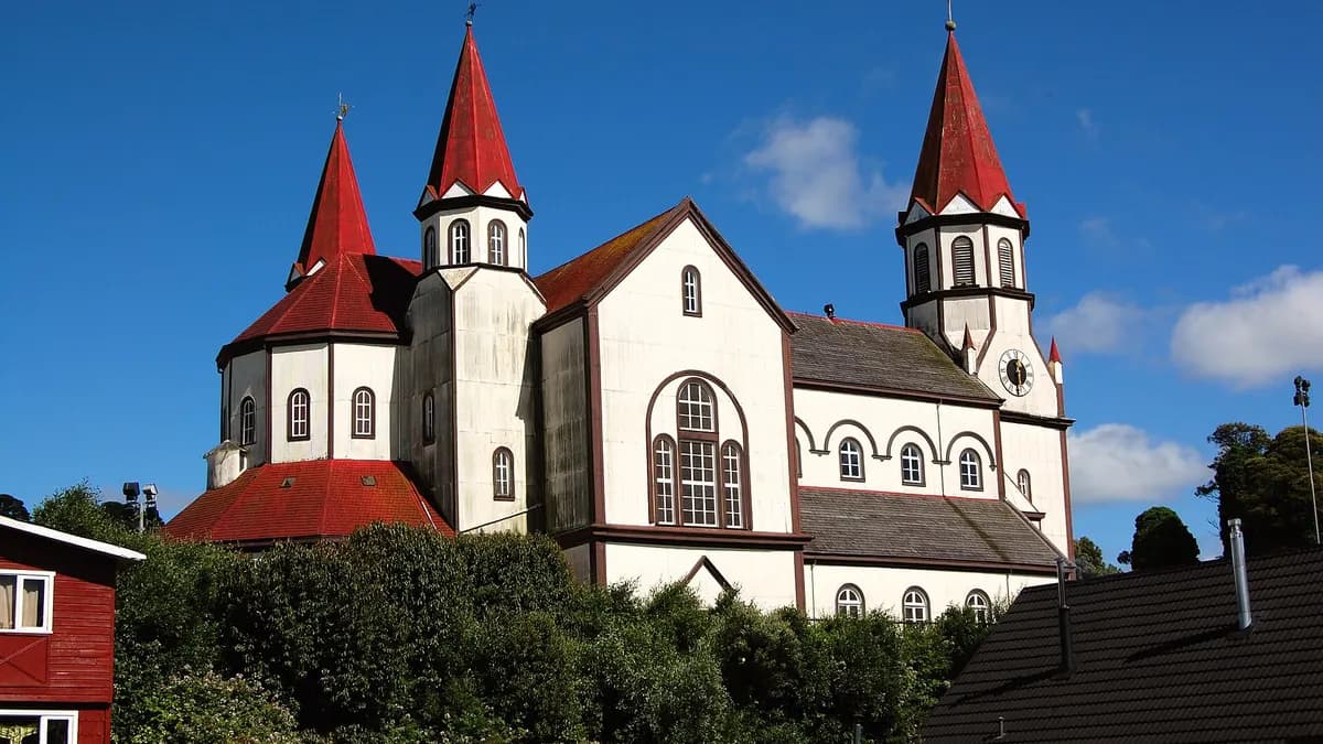 Templo de madera blanca con techumbre roja y torres en punta en lo alto de Puerto Varas