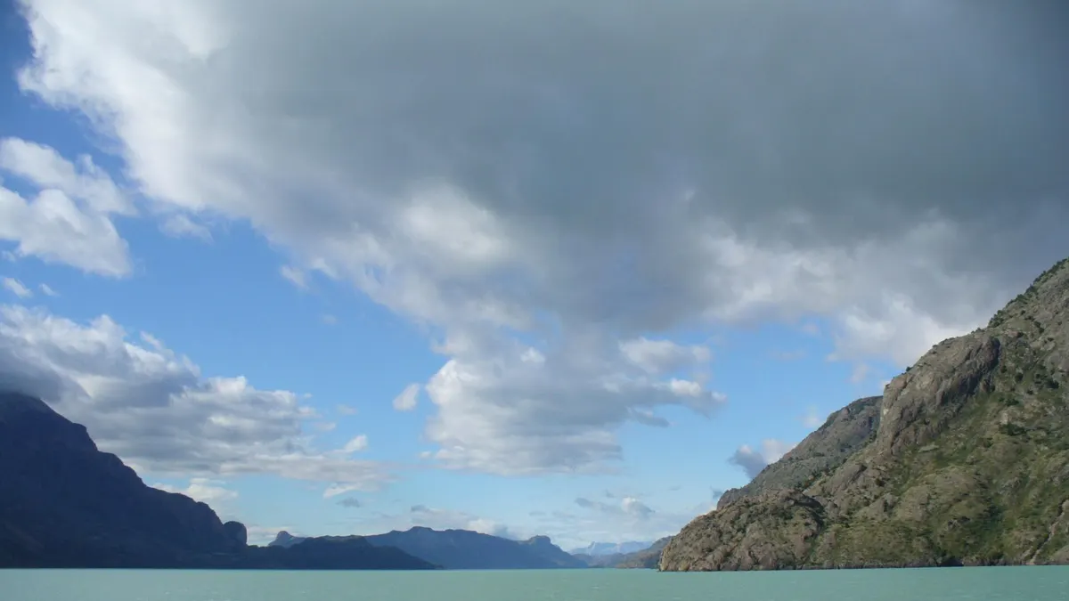 Aguas turquesa del lago O'Higgins rodeadas de montañas y nubes en Aysén