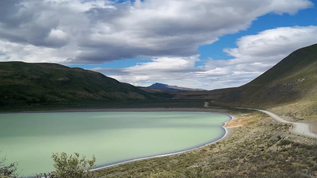 Camino de ripio junto a la Laguna Amarga, de agua verde, en el acceso a Torres del Paine