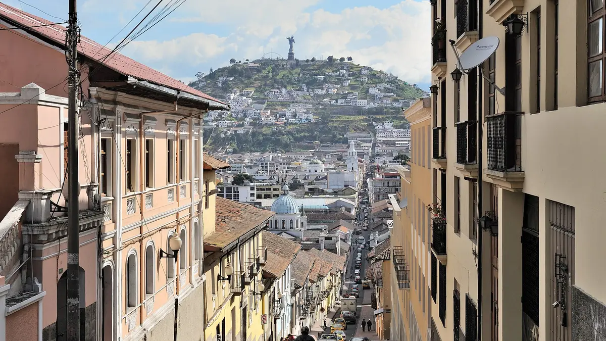 Calle empinada del centro histórico de Quito con la colina del Panecillo al fondo