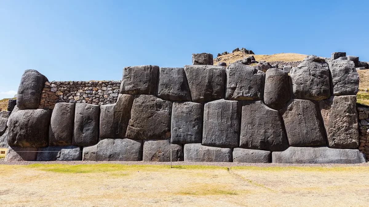 Muros de piedra incaica de Sacsayhuamán en las afueras de Cusco con pasto seco al frente