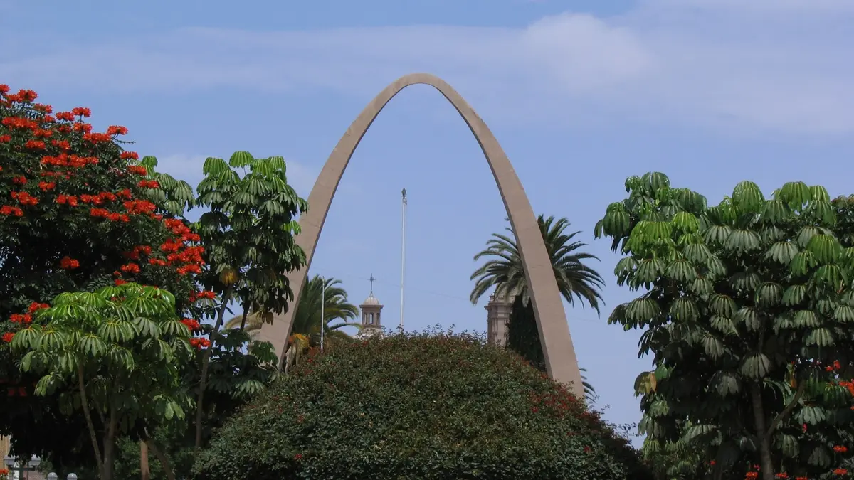 Arco Parabólico de Tacna rodeado de árboles con flores rojas