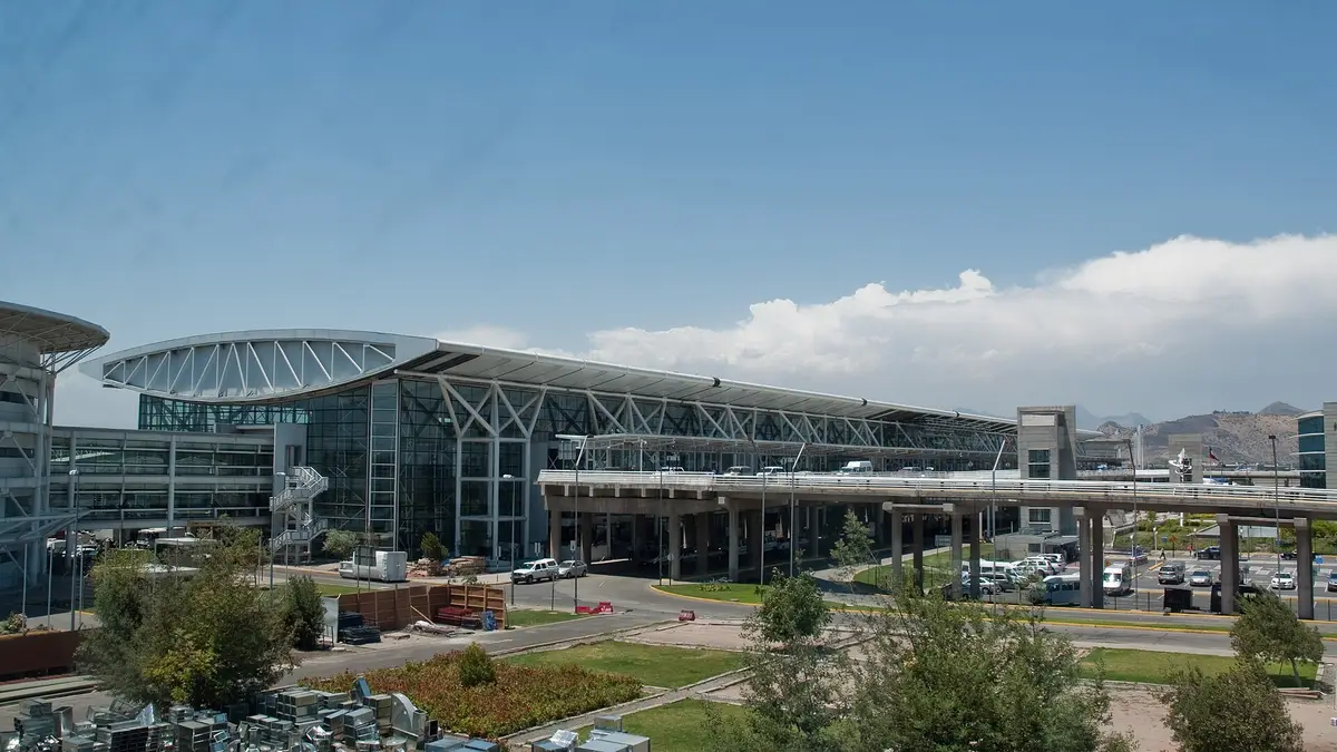 Fachada del terminal del aeropuerto de Santiago con vehículos en el acceso