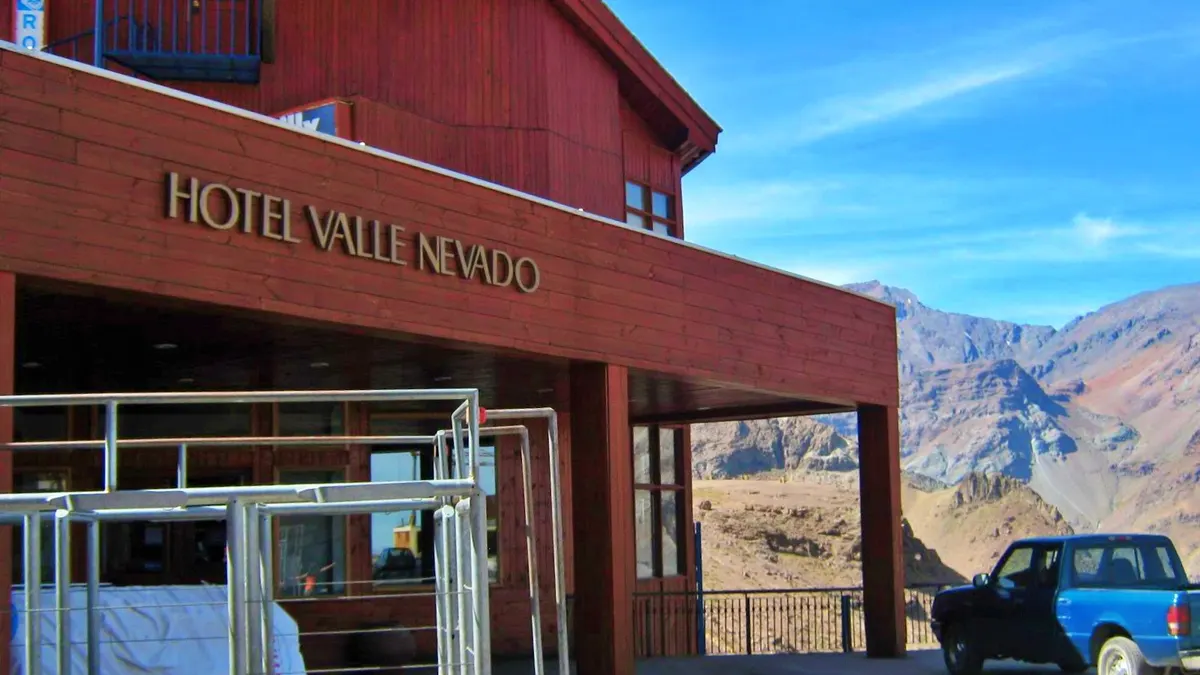 Esquiadores bajando por una pista ancha de Valle Nevado en día despejado