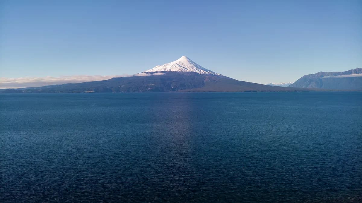 Cono blanco del Osorno reflejado sobre el Llanquihue desde la costa de Los Riscos